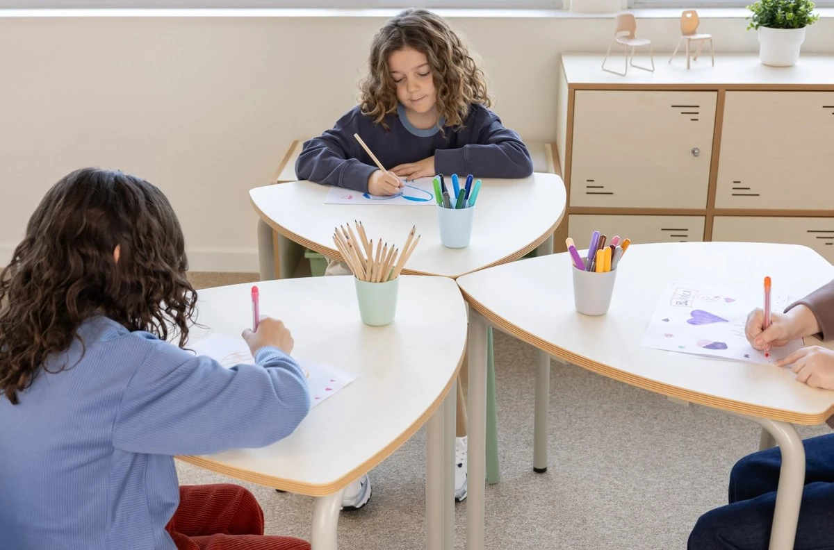 Kinder arbeiten gemeinsam an einer Gruppe gerundeter dreieckiger Schülertische