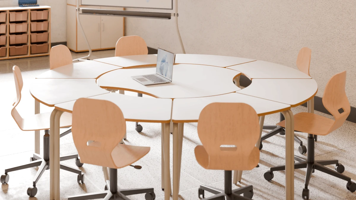 Gruppentisch mit drei Körperausschnitten und orangefarbenen Stühlen im Unterrichtsraum