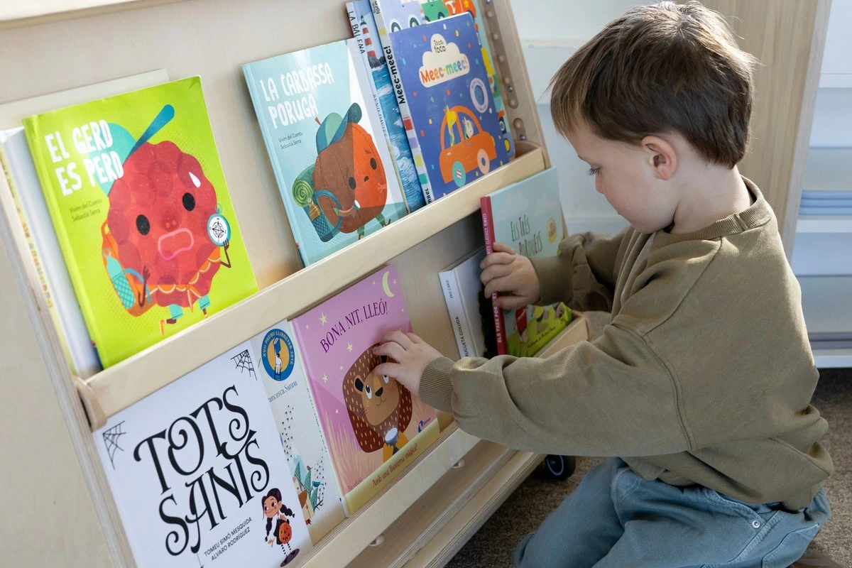 Kind wählt ein Buch am Bücherwagen TILA